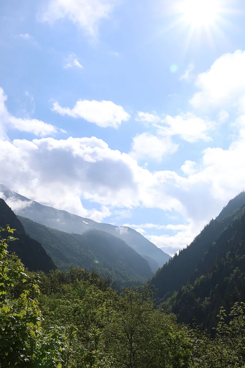 Een panoramisch uitzicht op valleien omringd door bergen en een helderblauwe lucht met enkele wolken.